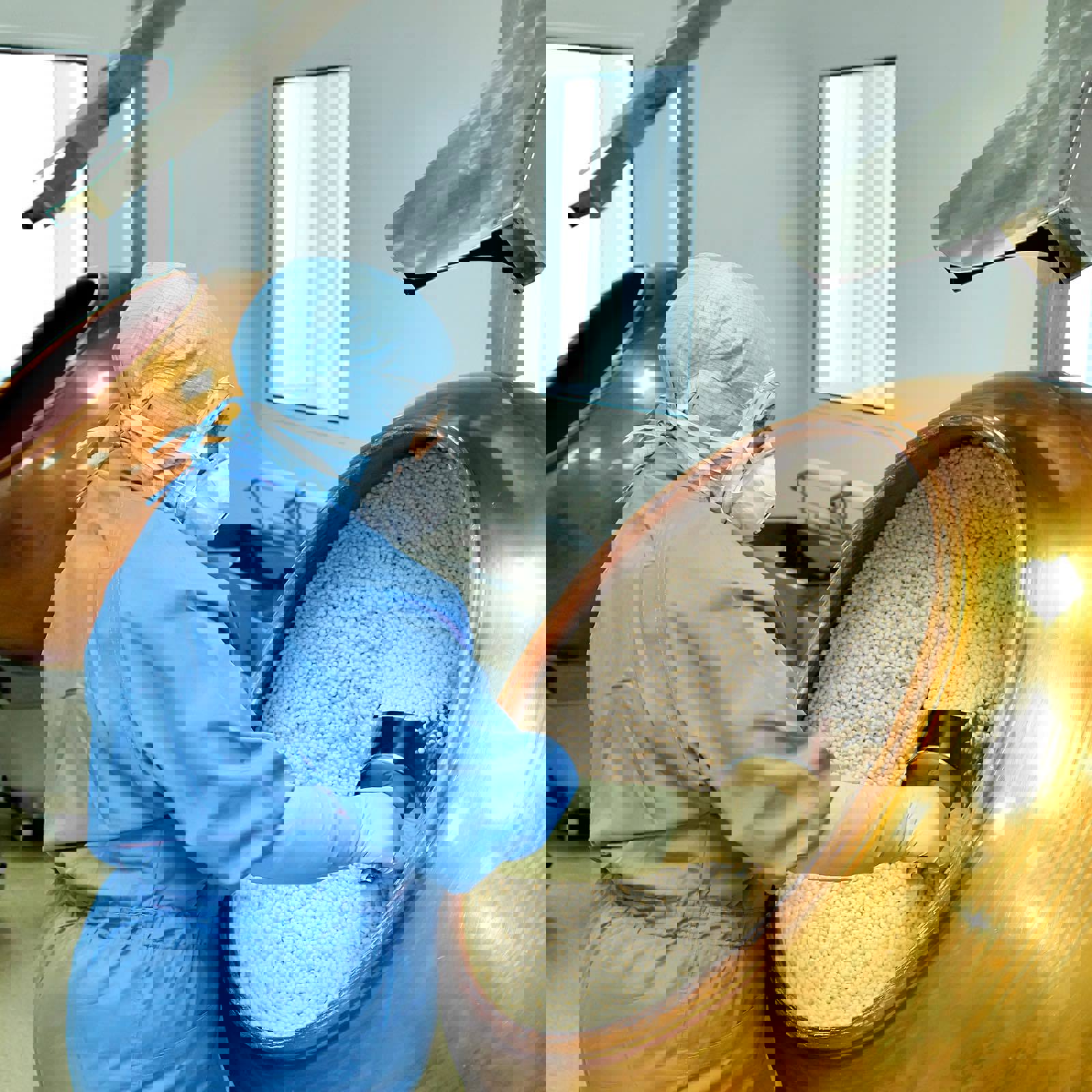 Worker scooping granules in a factory