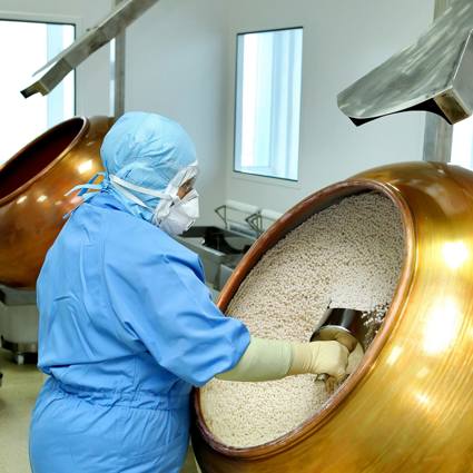 Worker scooping granules in a factory