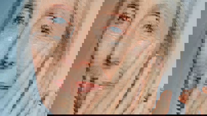 Senior Woman Applying Cream To Face