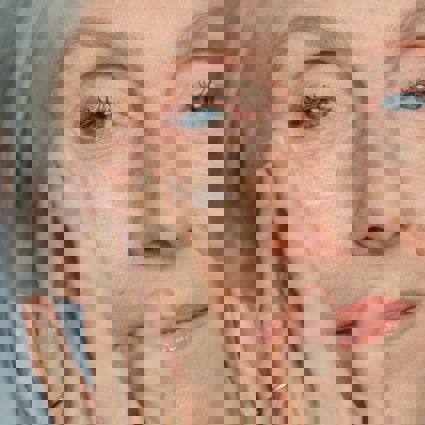 Senior person applying cream to face