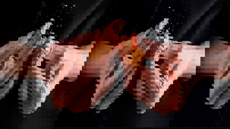 Hands Breaking Biscuit Into Two Pieces