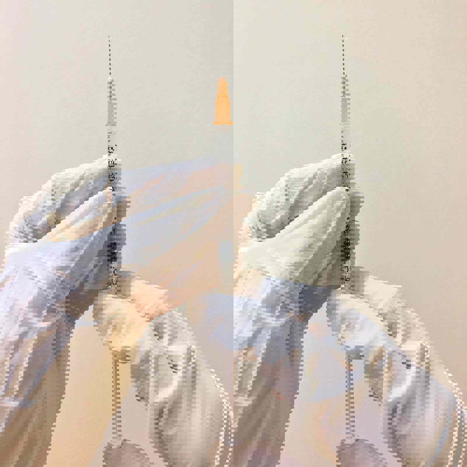 Person wearing gloves preparing a syringe 