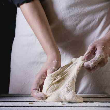 Baker stretching dough in hands
