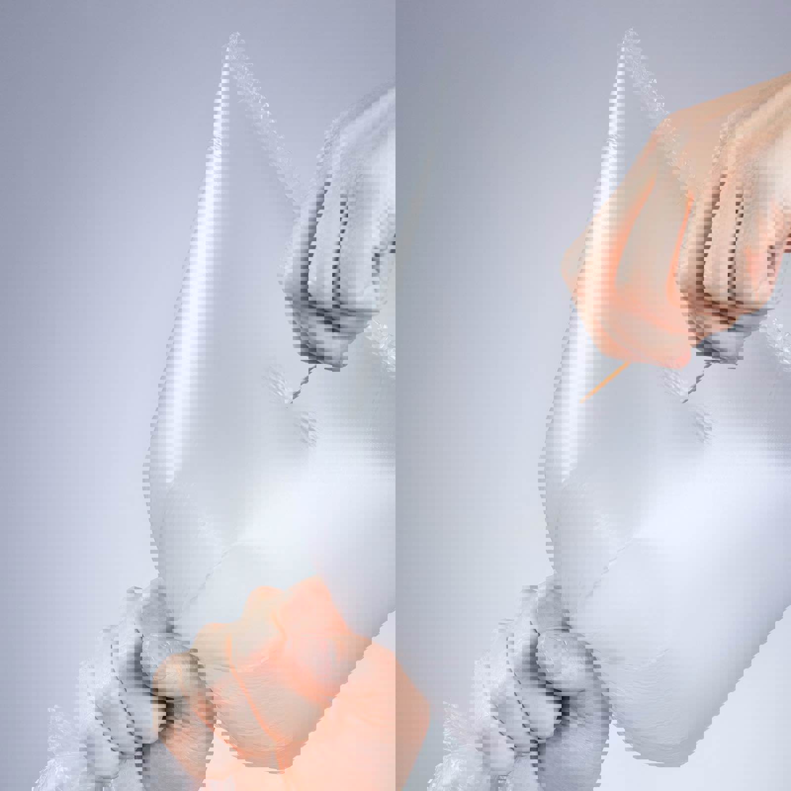 Person popping plastic bag with a toothpick