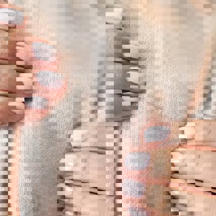 Person assessing the softness of a woollen material with their hands