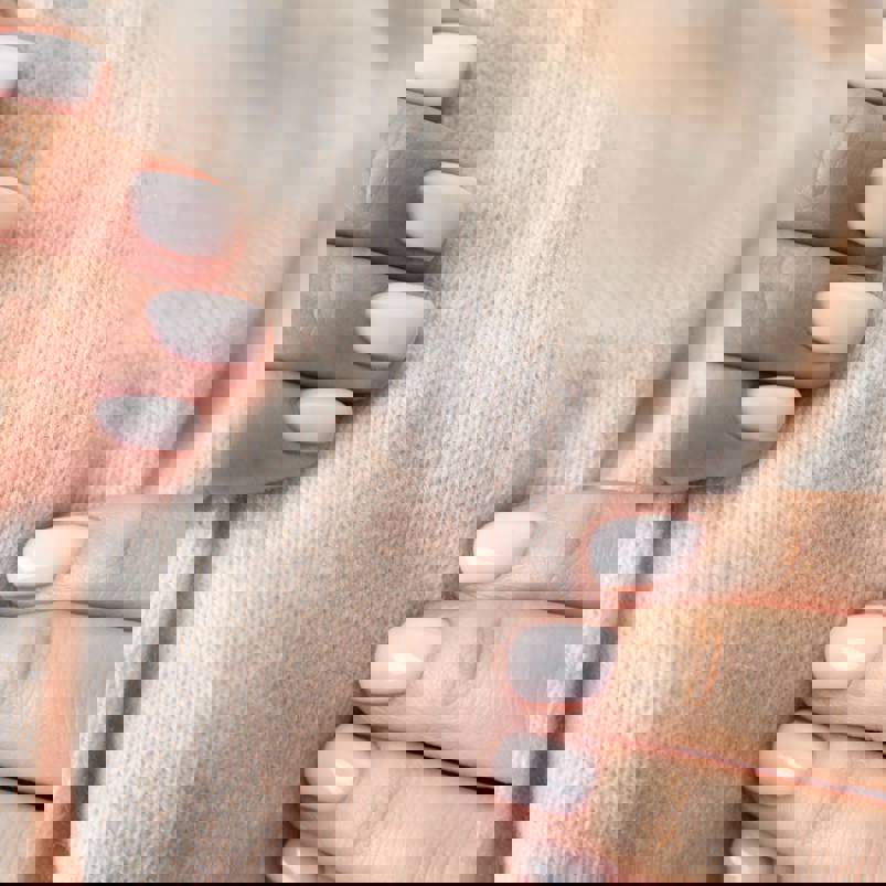 Person assessing the softness of a woollen material with their hands