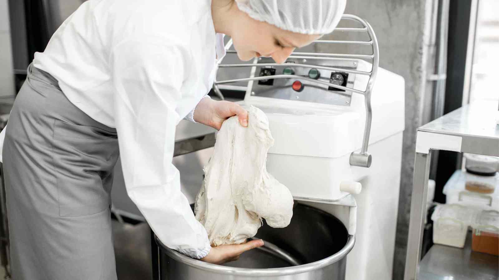 Baker bringing dough together with hands over a bowl