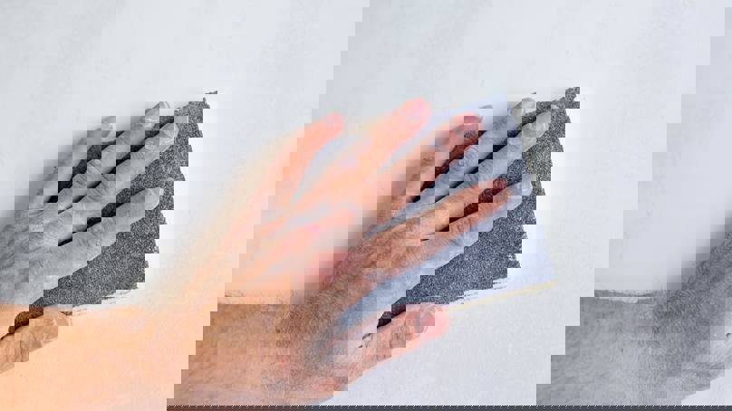 Person Sanding A Wall