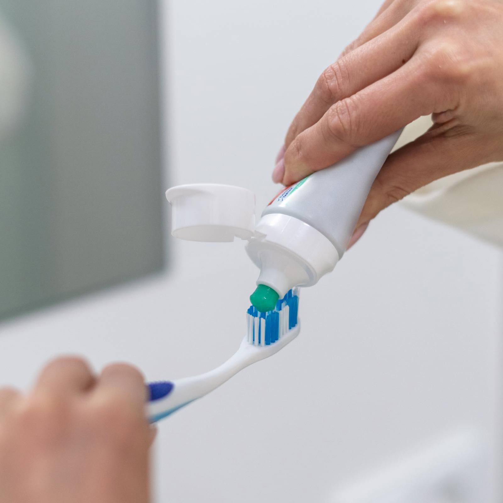 Person applying toothpaste to a toothbrush