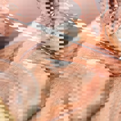 Person slicing raw chicken breast with a knife