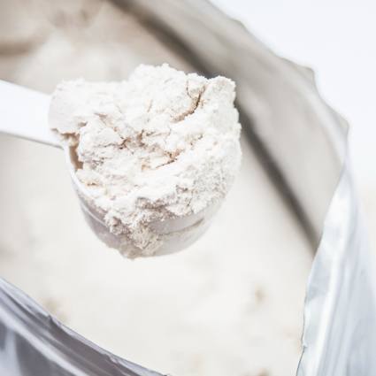 Person scooping protein powder from a bag