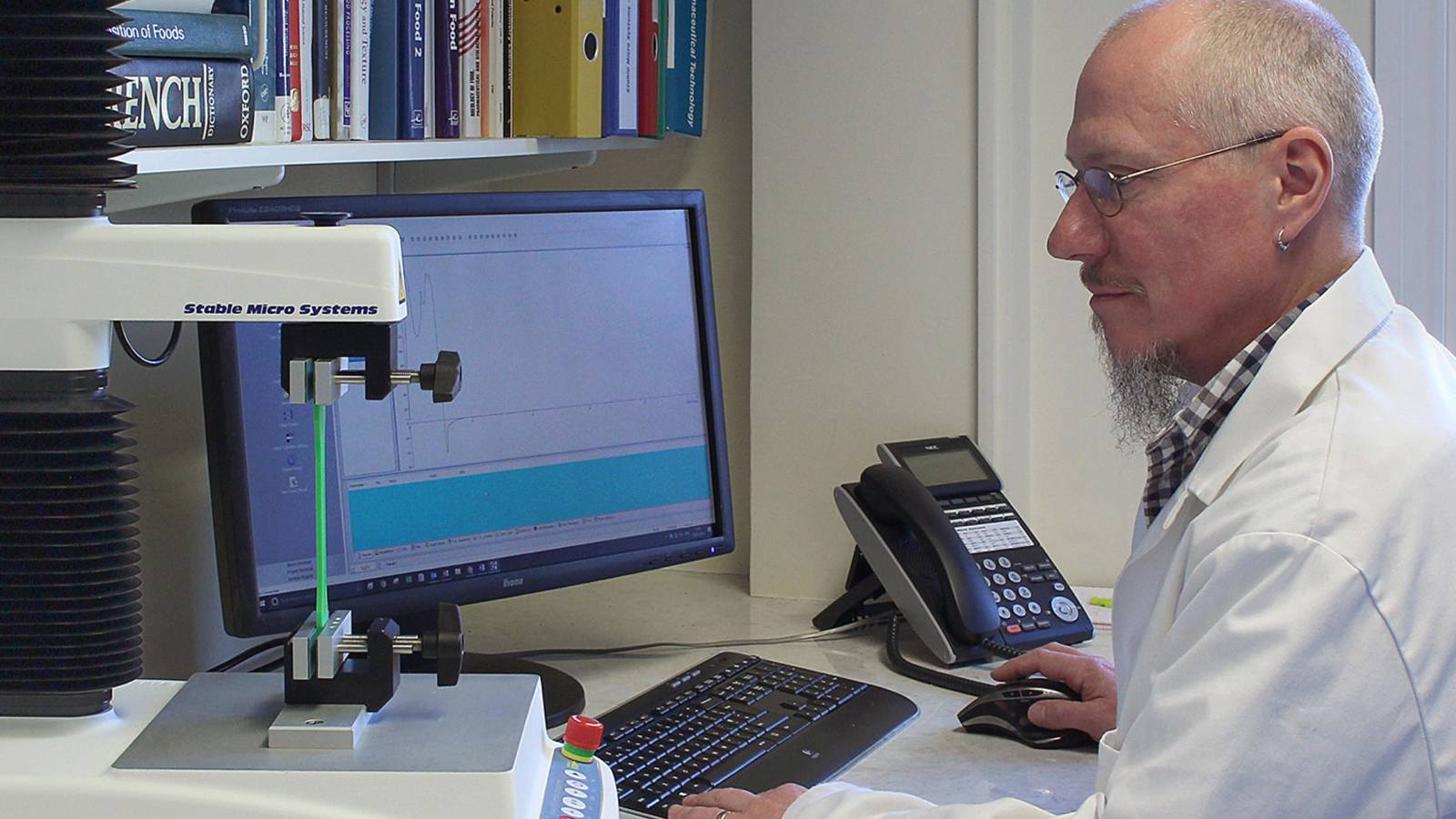 Man in white coat sitting at PC using Texture Analyser 