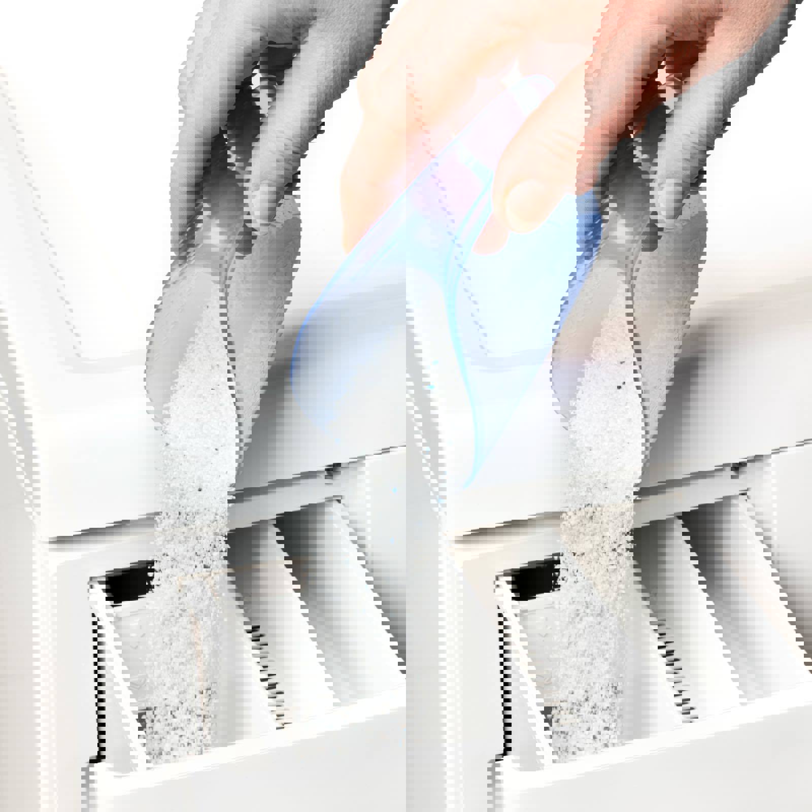 Person tipping washing powder into a washing machine drawer