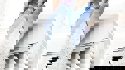 Person Pouring Washing Powder Into Tray Of Washing Machine