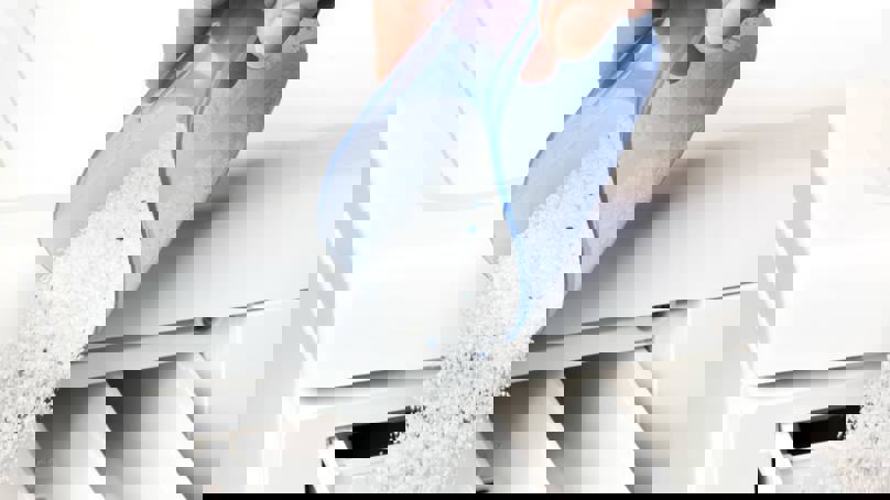 Person Pouring Washing Powder Into Tray Of Washing Machine