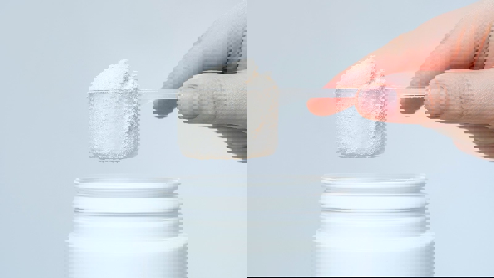Person holding a scoop of protein powder demonstrating cohesion