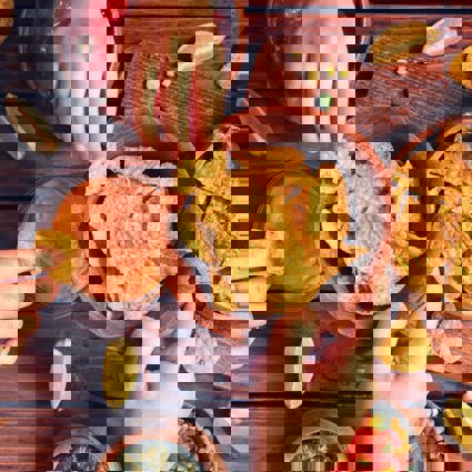 People sharing corn chips and dips