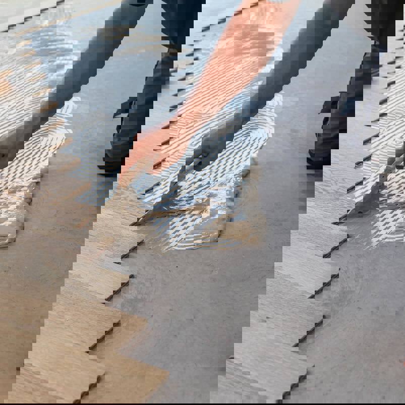 Person applying adhesive to floor to lay wooden flooring