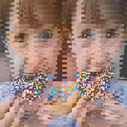Boy biting into donut with sprinkles