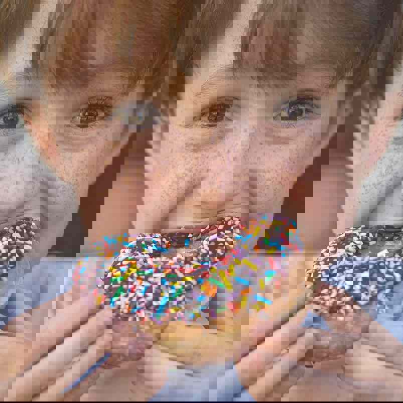 Boy biting into donut with sprinkles