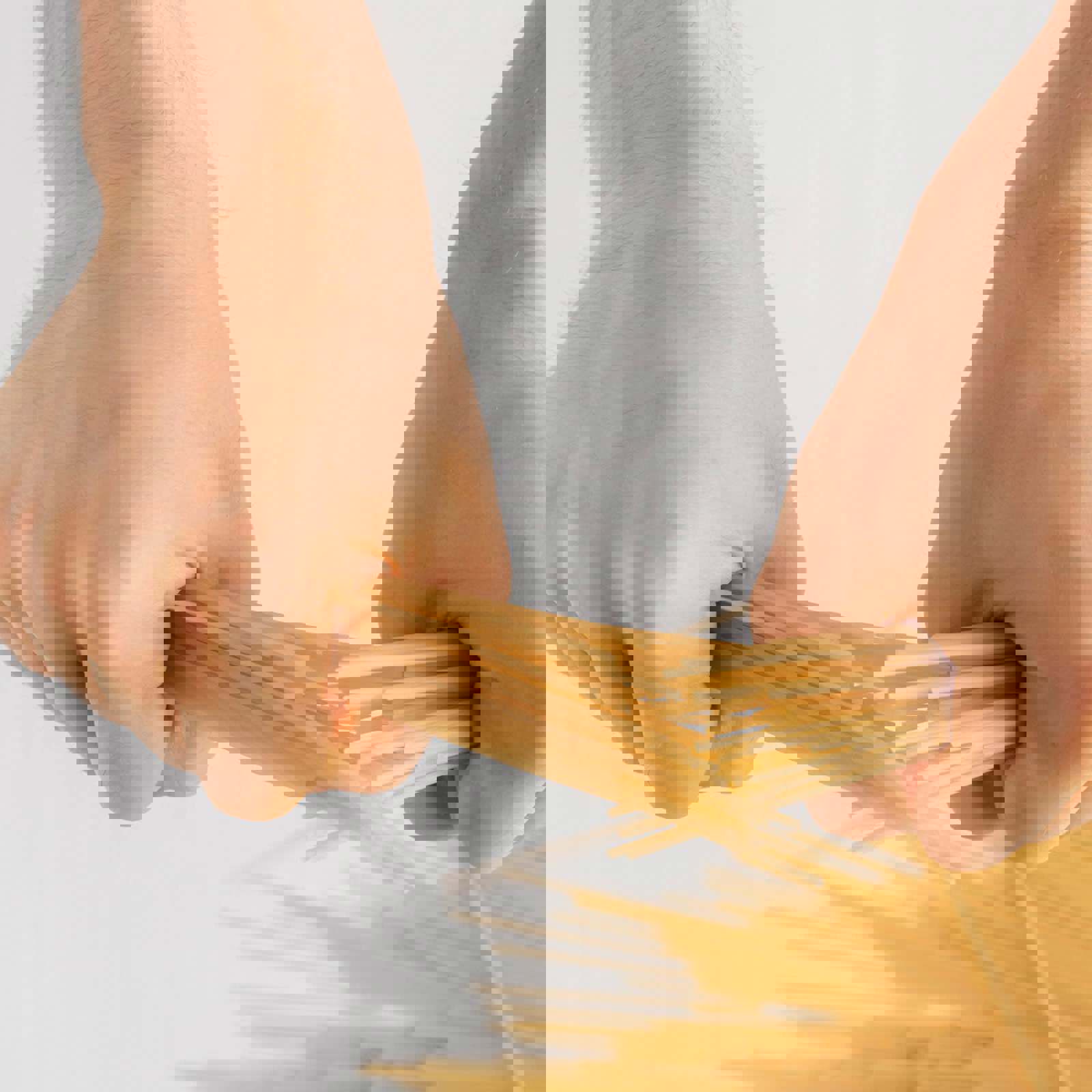 Person snapping spaghetti in half