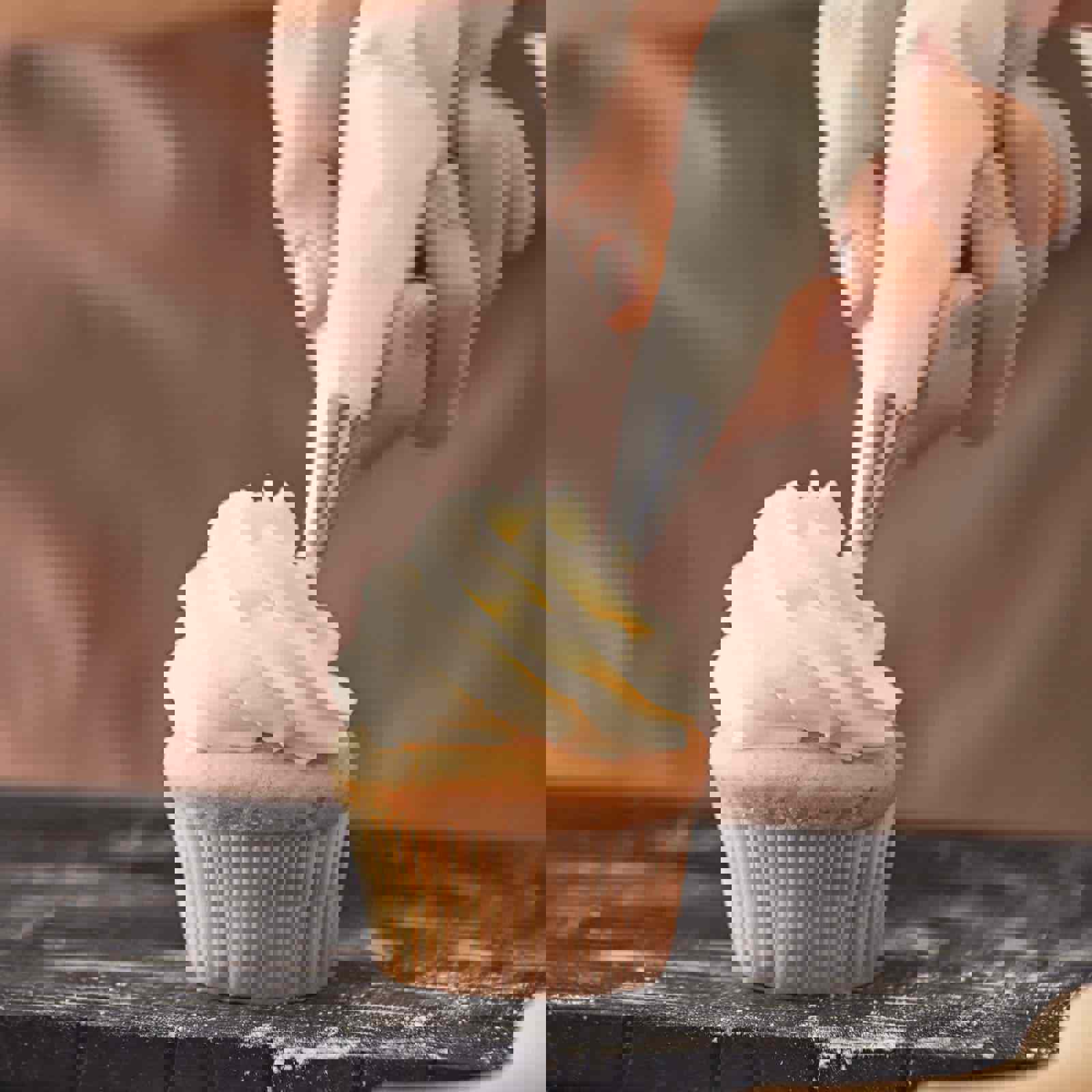 Baker piping icing on to a cupcake