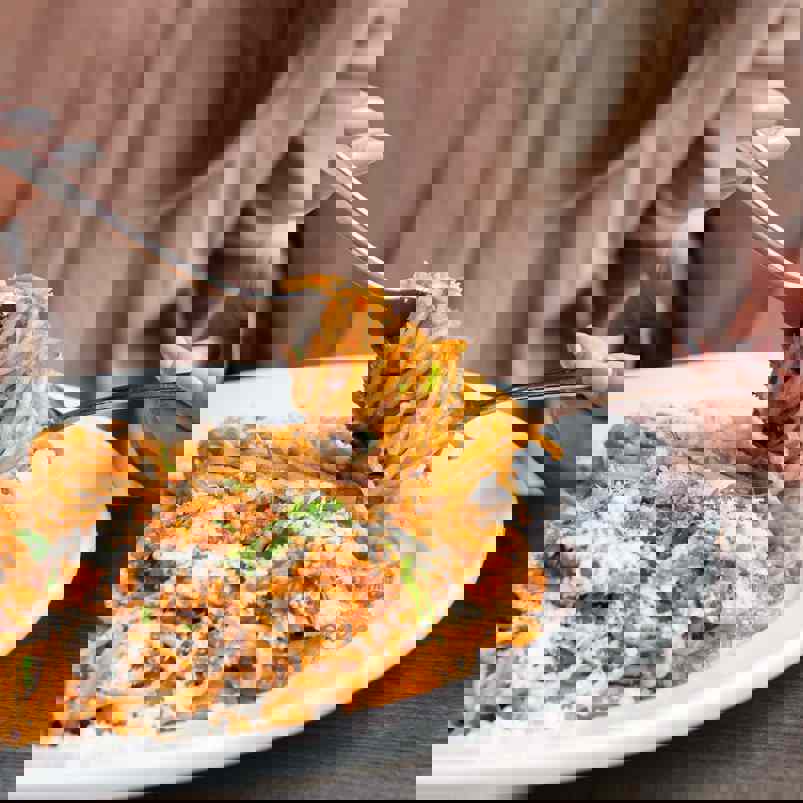 Person twirling cooked spaghetti onto a fork