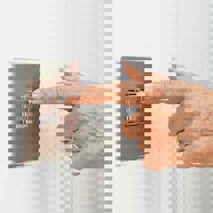 Person switching on a wall mounted switch