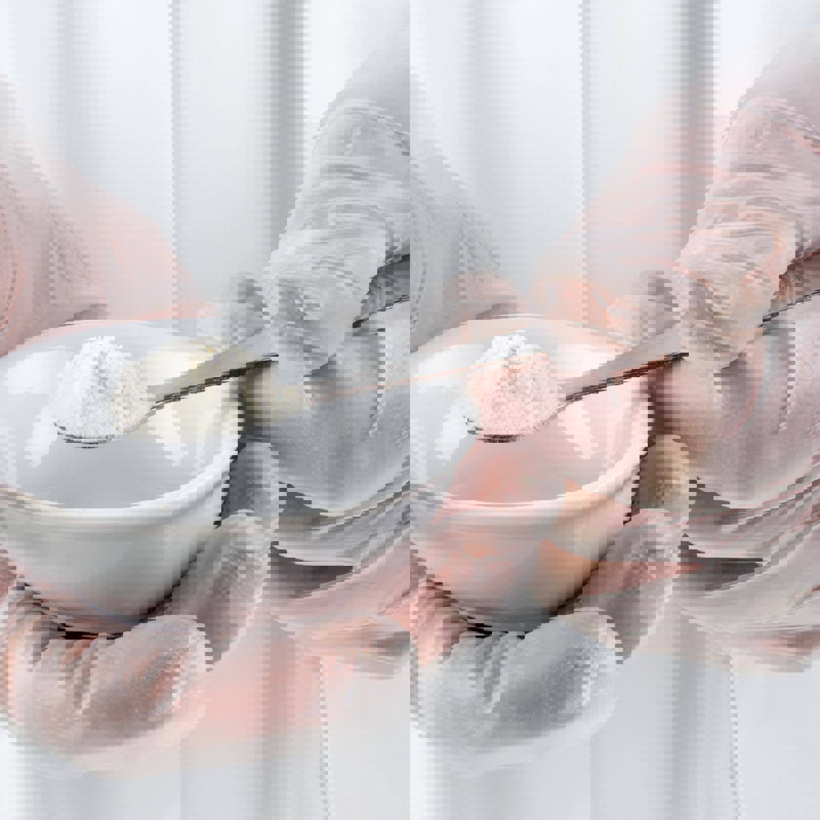 Lab technicial holding spoon of white powder