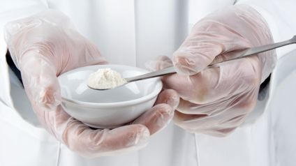 Lab Technician Holding A Scoop Of White Powder