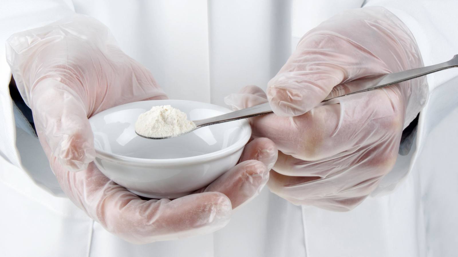Lab technicial holding spoon of white powder