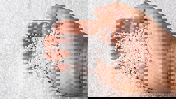 Person Scooping Polymers In Pellet Form With Hand